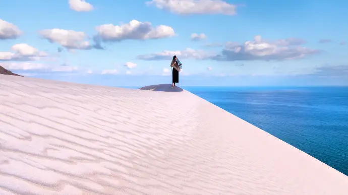 a person standing on top of a sand dune